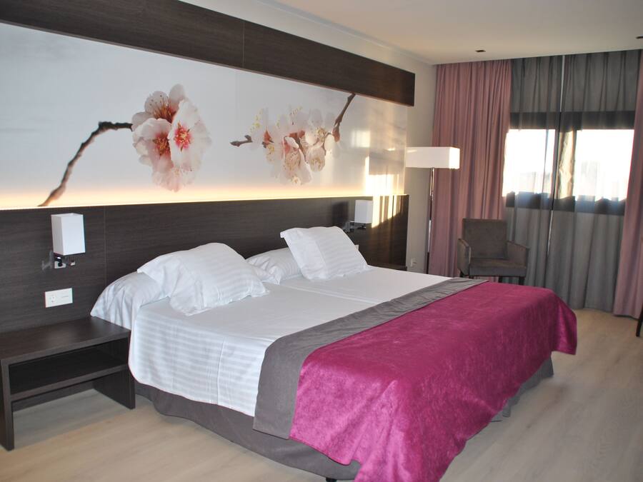 Una habitación de hotel moderna con una cama grande, una mesita de noche, un escritorio y una silla.