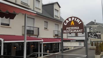 Un restaurant-pizzeria avec une terrasse et un menu affiché.
