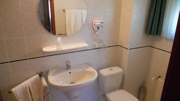 Une salle de bain avec un lavabo, des toilettes et un miroir.