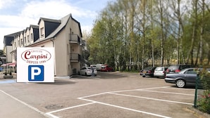 Un estacionamiento de hotel con espacios delimitados y un cartel que indica Hotel CARPINI Bascharage.