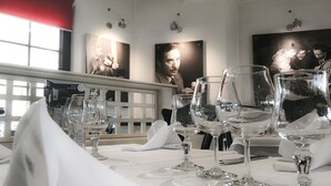 Comedor con mesas dispuestas para una comida, con cristalería transparente y manteles blancos.