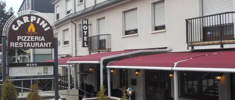 Un edificio con un letrero que dice 'Carpini Pizzeria Restaurant' y un letrero de 'Hotel'.