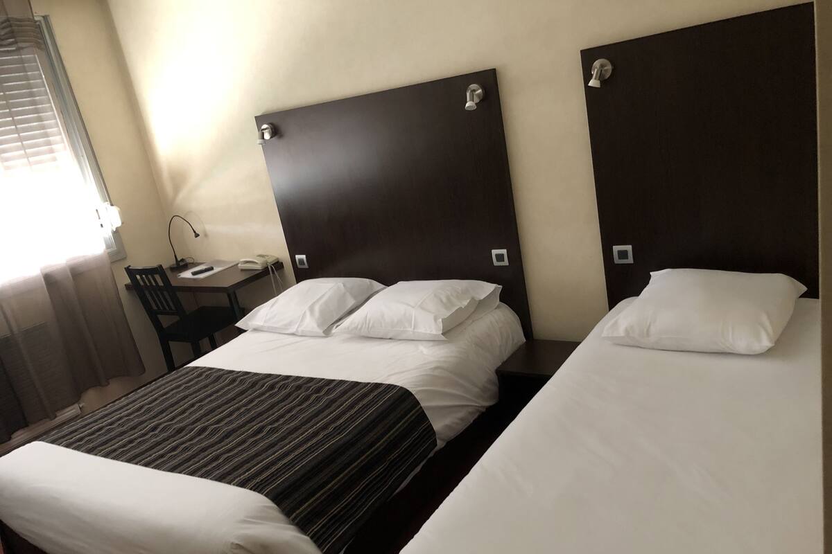 A hotel room with two beds, a desk, and a chair.