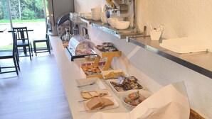 A buffet setup with various food items, including bread, pastries, and a coffee station. - Adonis Lyon Est Hôtel Artys (Saint-Priest)