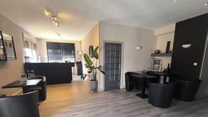 A modern kitchen with a central island, a dining area with black chairs, and a potted plant. - Adonis Lyon Est Hôtel Artys (Saint-Priest)