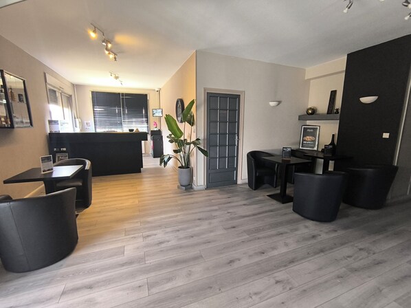 Une cuisine moderne avec un îlot central, un coin repas avec des chaises noires et une plante en pot.