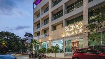 Un hotel de varios pisos con un llamativo letrero de neón que dice "SOHO PLAYA".
