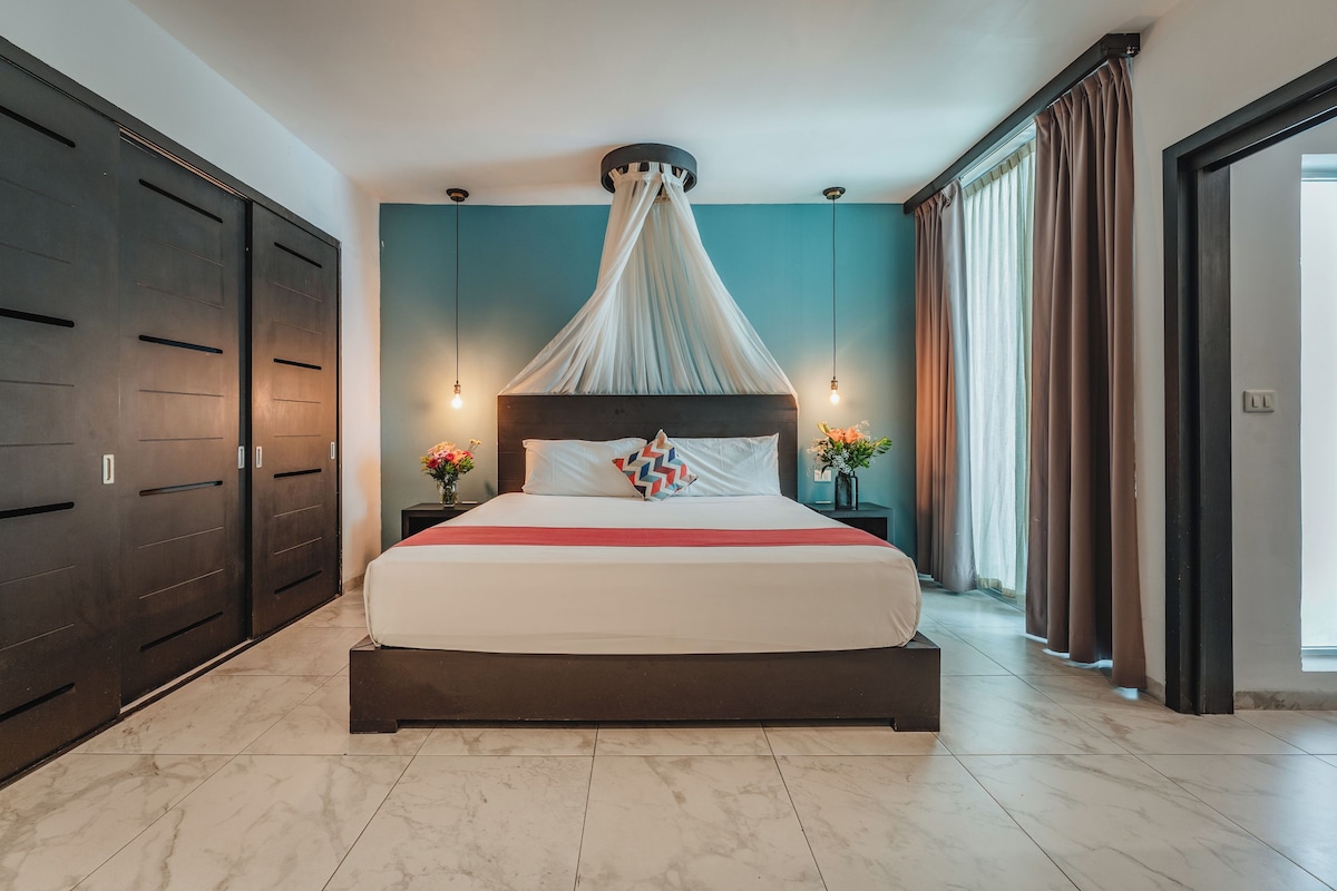 A modern bedroom with a large bed, dark wooden wardrobe, and a canopy bed.
