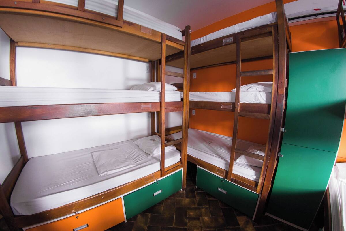 A bunk bed room with wooden frames and green storage drawers.