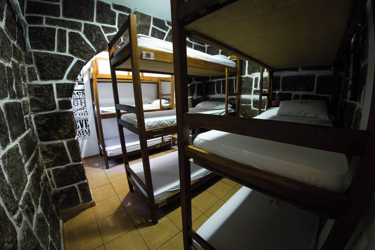 A bunk bed room with stone walls and wooden bunk beds.