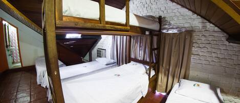 Un dormitorio con literas, pared de ladrillo y techo de madera.