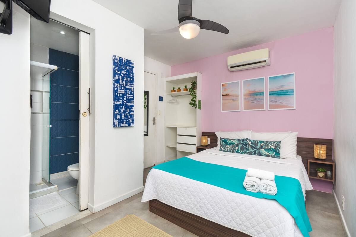A bedroom with a bed, a wardrobe, a bathroom, and a ceiling fan.