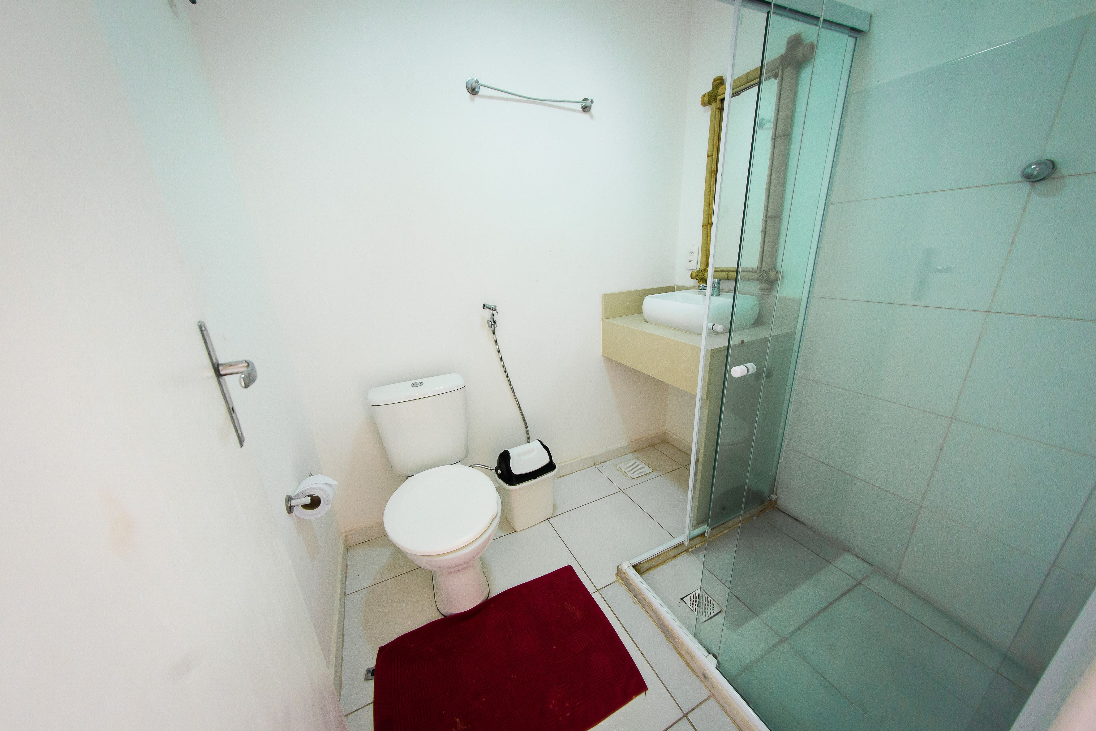 Een kleine badkamer met toilet, wastafel en douchecabine met glazen wanden.