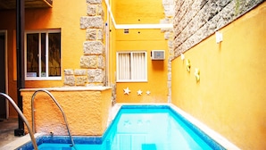 Une piscine avec un mur en pierre et une fenêtre ornée de barreaux en métal.