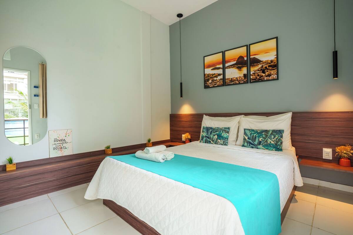 A modern bedroom with a large bed, a wooden headboard, and a cityscape artwork on the wall.
