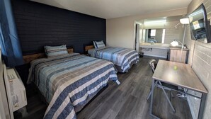 A room with two beds, a desk, a mirror, and a TV. - Belle-Aire Motel (Globe)