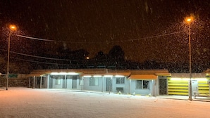 A building with multiple rooms, a covered outdoor area, and a snow-covered ground. - Belle-Aire Motel (Globe)
