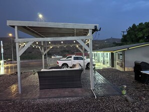 A covered outdoor area with a white pickup truck parked under a pergola with string lights. - Belle-Aire Motel (Globe)