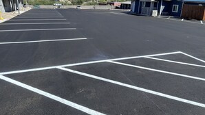 A parking lot with marked spaces, a motel sign, and a building with a blue roof. - Belle-Aire Motel (Globe)