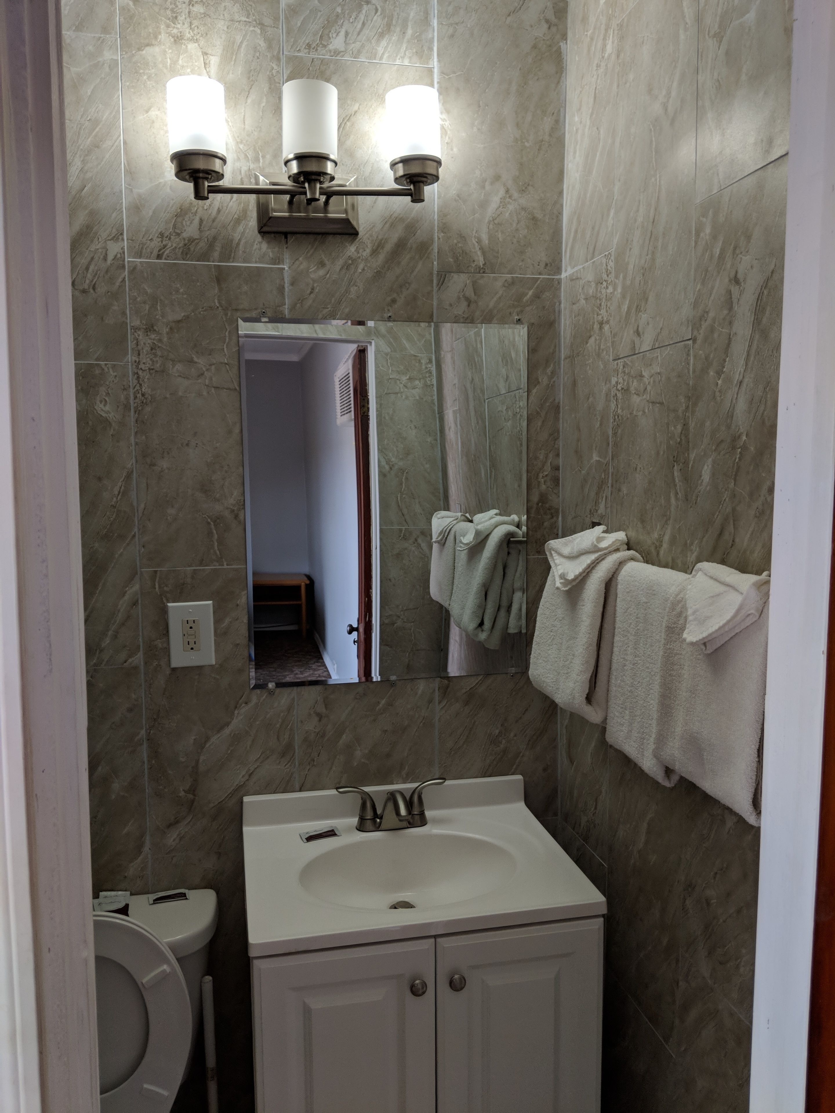 A bathroom with a white sink, a mirror, and a towel rack.