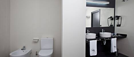 Un baño moderno con bidé, inodoro y lavamanos dobles.