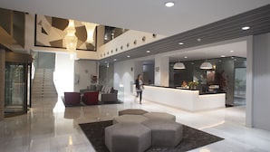 A spacious lobby with a modern design, featuring a reception desk, seating area, and a staircase leading to upper floors. - Hotel K10 (Urnieta)