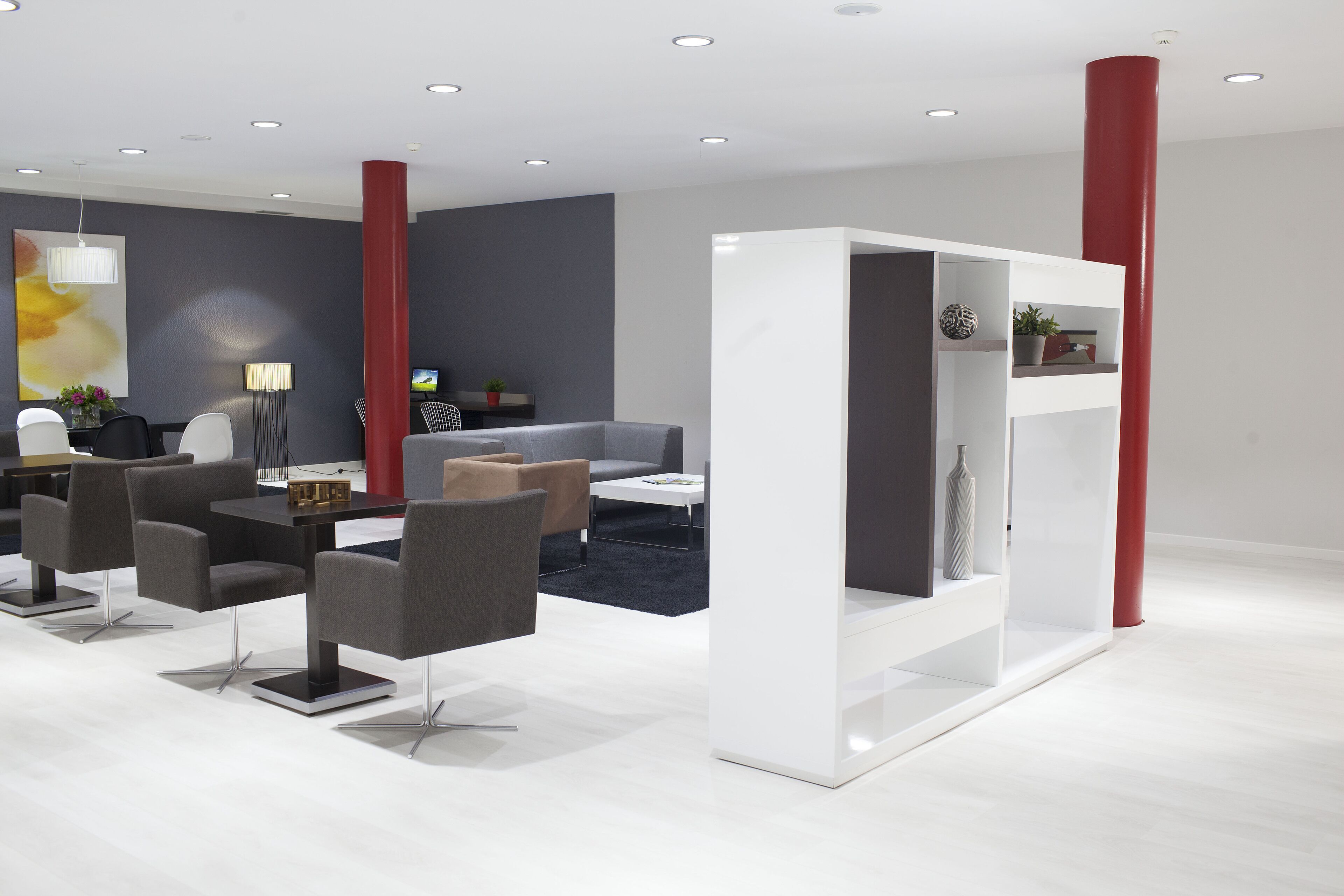 Un interior moderno con comedor, sofás y una estantería blanca.