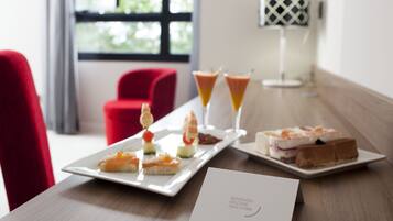 A dining table with a white plate of appetizers, two martini glasses, and a dessert plate. A welcome card is placed on the table.