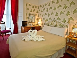 Ein Hotelzimmer mit Bett, Fernseher, Schreibtisch mit Lampe und Stuhl.