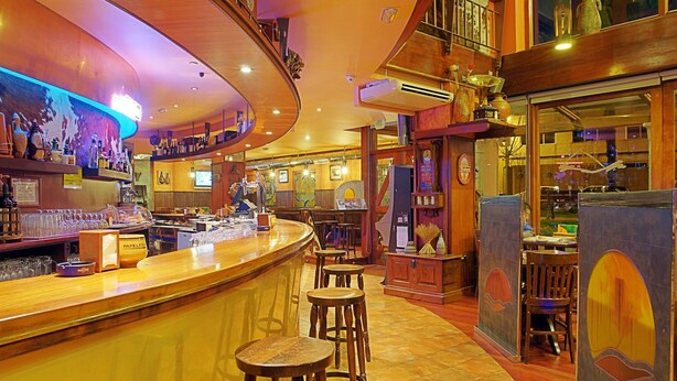 A bar area with stools, a counter, and various bottles and glasses. - Hostal Bríos (Lugo)