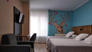 A hotel room with a bed, two chairs, a desk, a television, and a mural of a deer on the wall. - Hostal Bríos (Lugo)