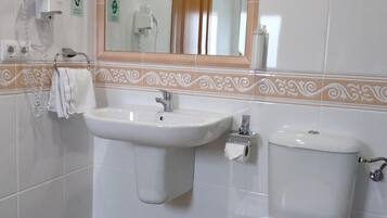 Un bany amb dues dutxes, un vàter i un mirall.