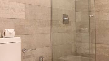 Un baño moderno con inodoro, bidé y ducha con mampara de vidrio.