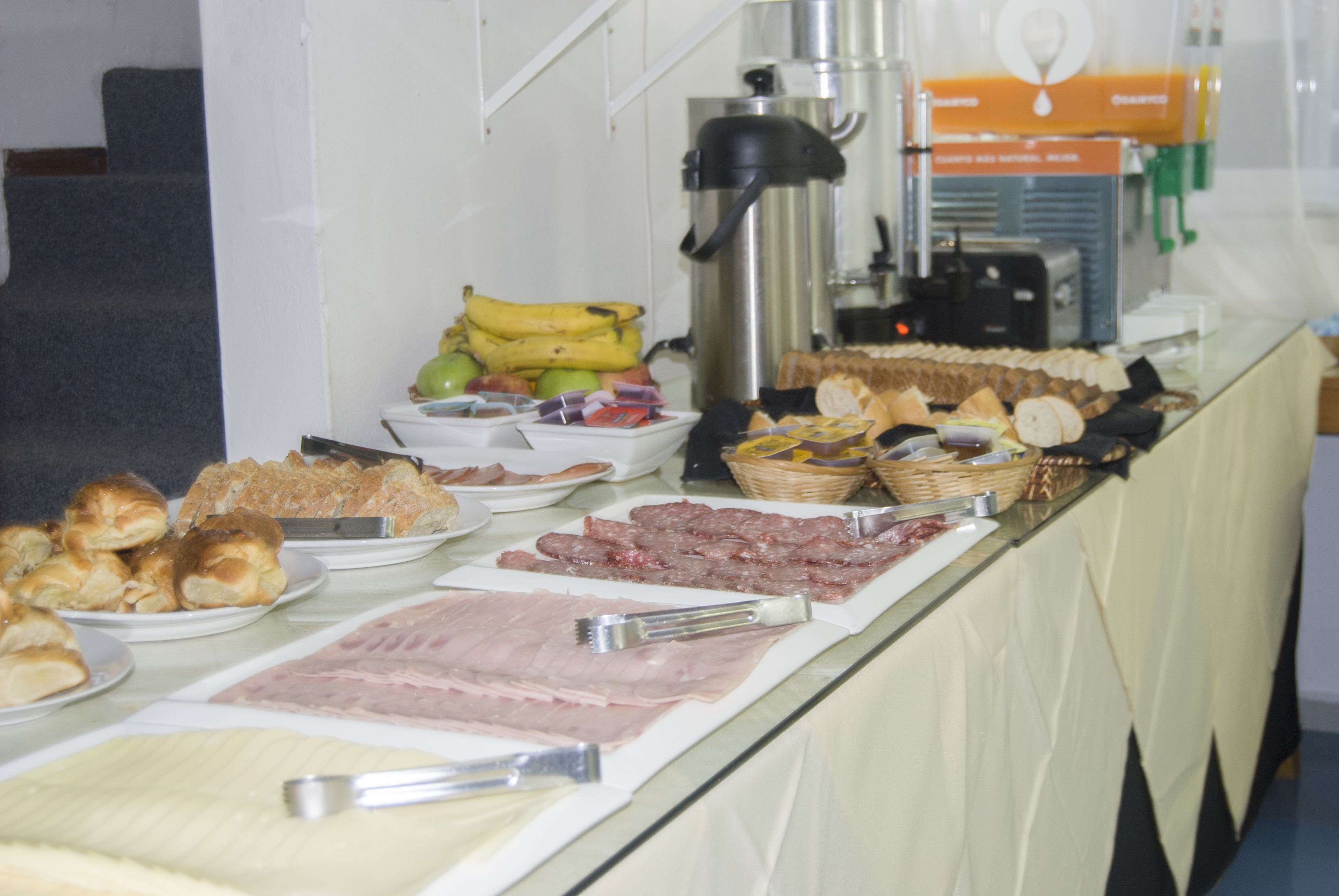 A buffet with various food items including bread, pastries, and meats.