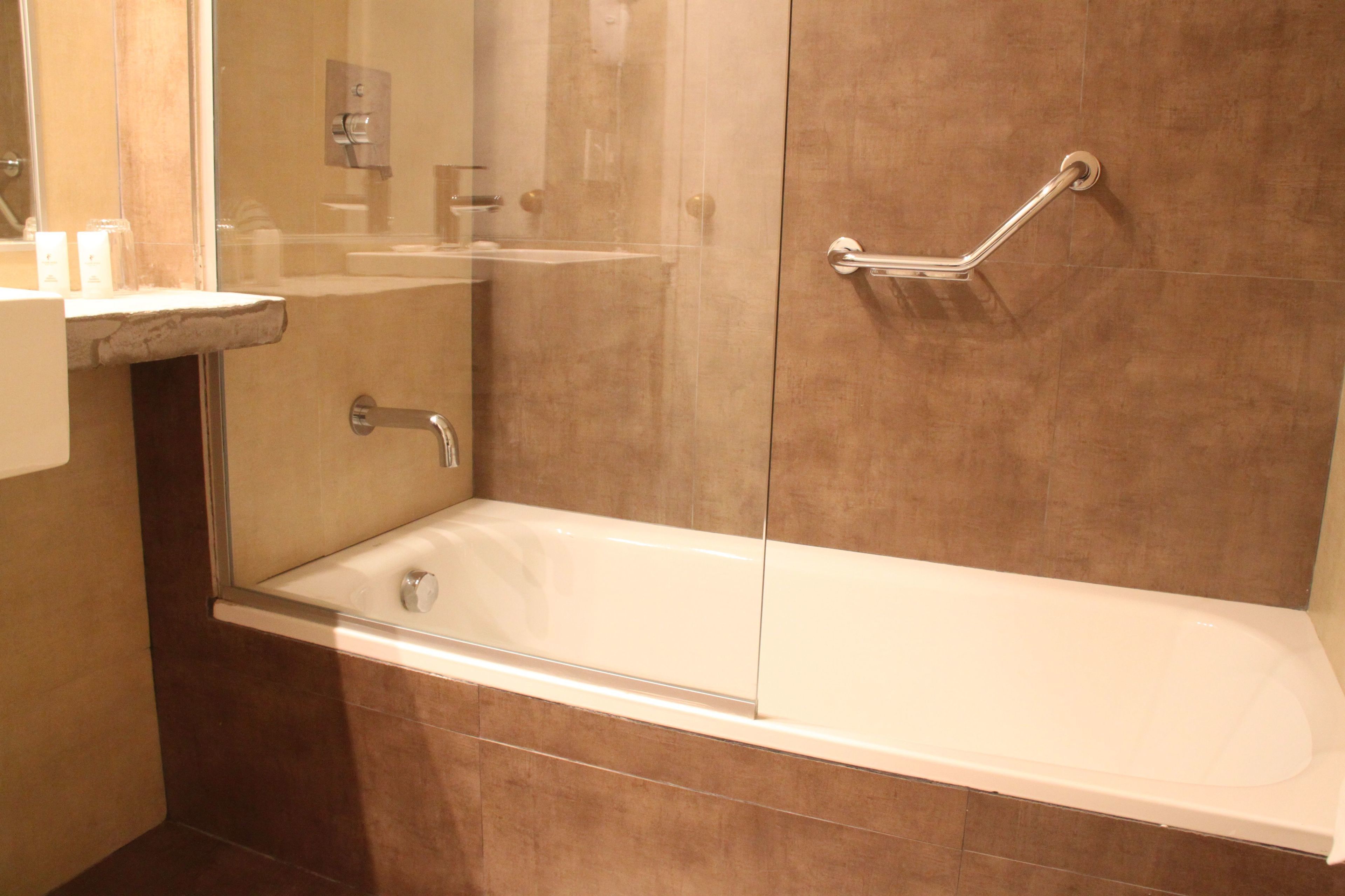Un baño moderno con bañera, cabina de ducha de vidrio y barra de apoyo.