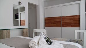 A modern hotel room with a neatly made bed, a glass-topped table, and a wooden panel wall. - Hotel Florinda (Punta del Este)