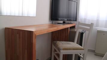 A wooden desk with a television, a white chair, and a white cabinet.