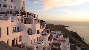 A coastal building with multiple balconies overlooking the sea, featuring a unique architectural style with white walls and arches. - Hotel Florinda (Punta del Este)