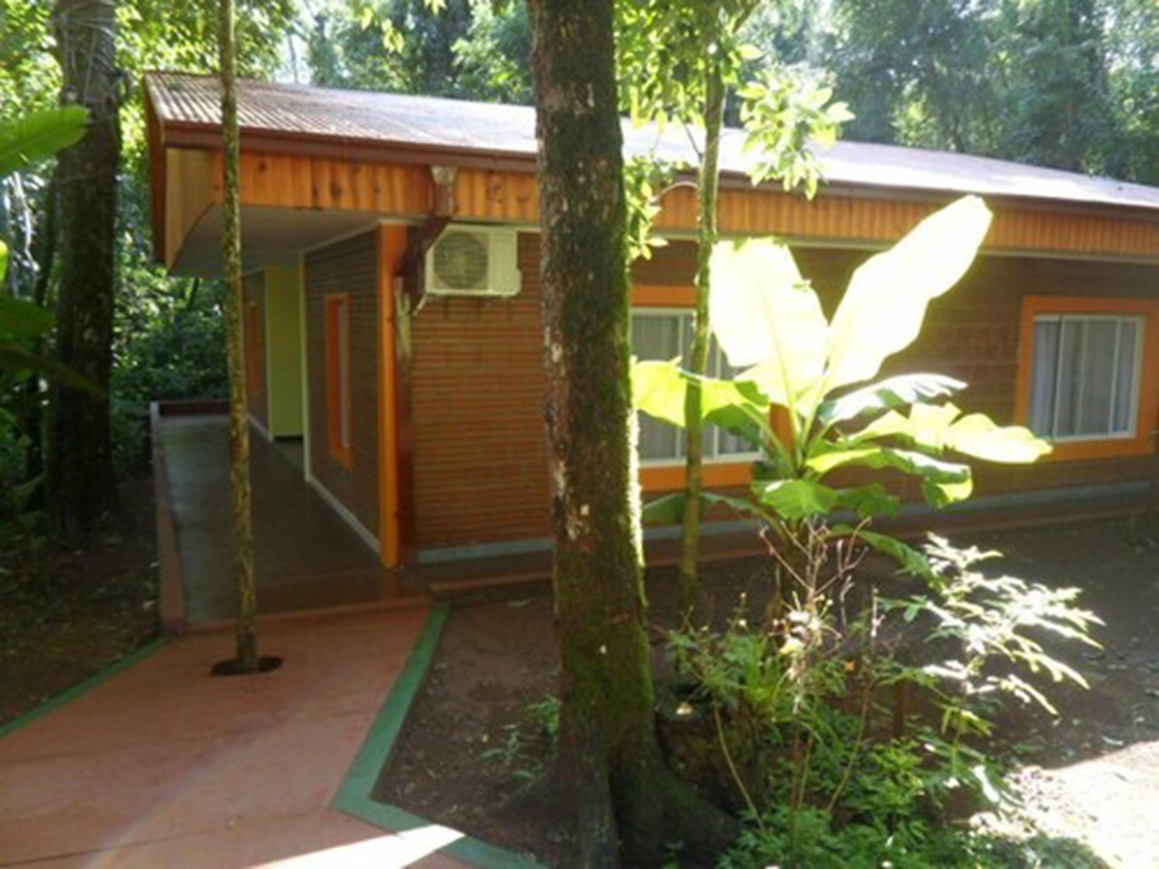 A wooden cabin with a covered porch, surrounded by trees and greenery.