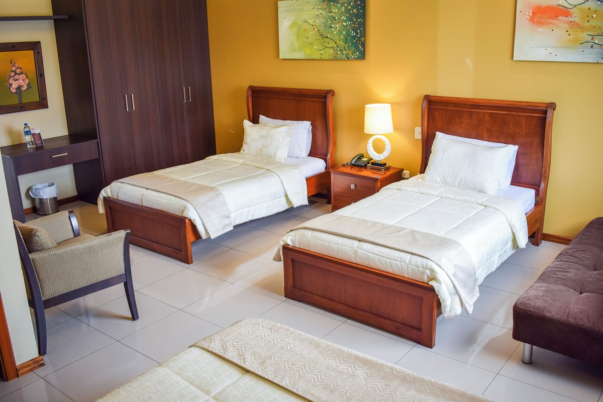 Ein Hotelzimmer mit zwei Betten, einem Schreibtisch, einem Sessel und einer Couch.
