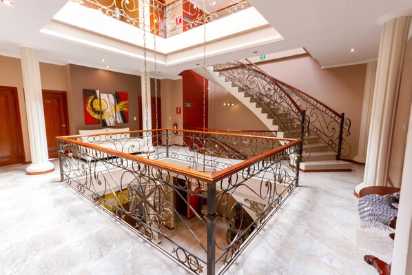 Un vaste atrium doté d’un espace central ouvert, d’un escalier orné de rampes en métal ouvragé et d’une mezzanine.