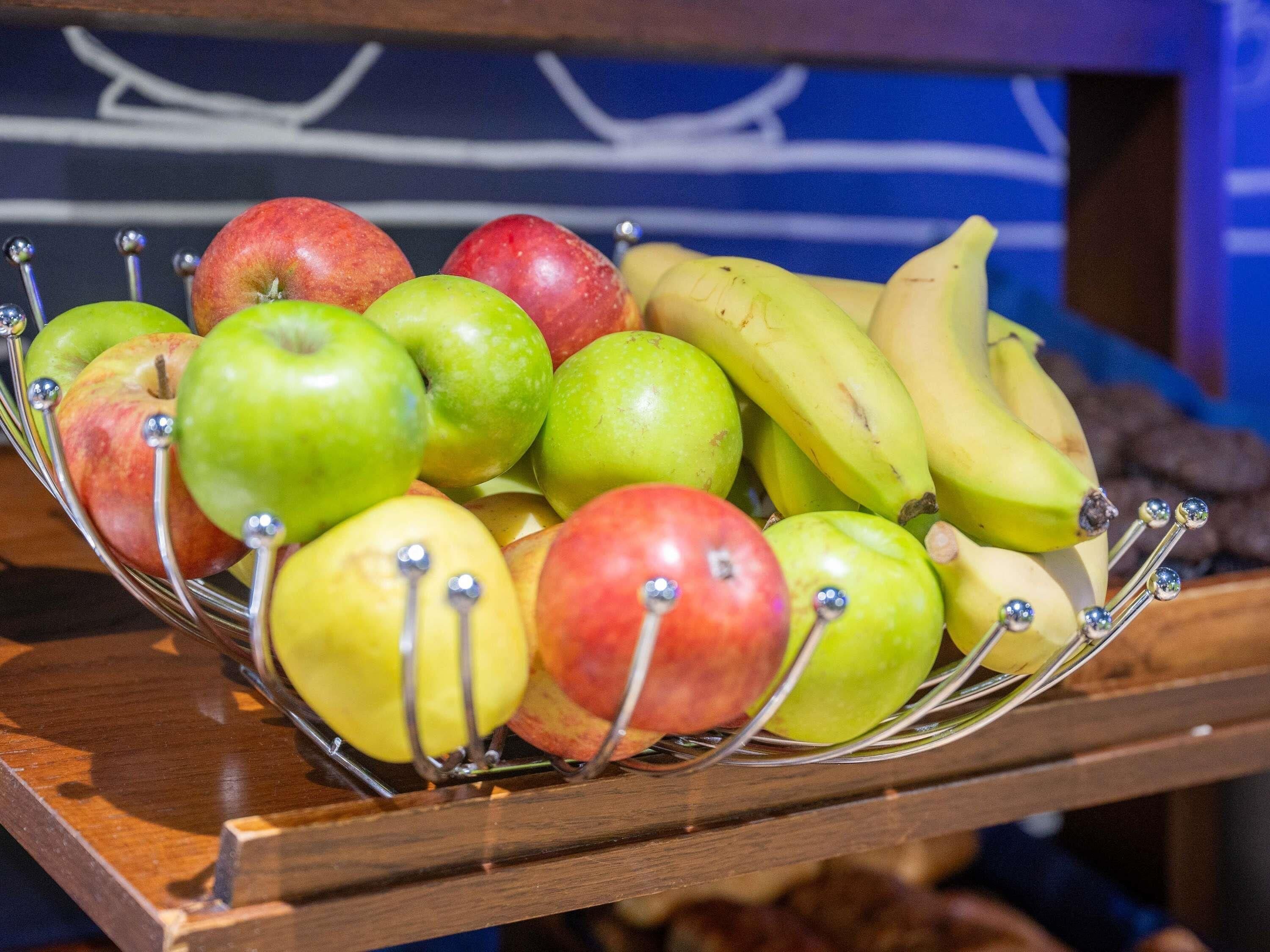 A fruit bowl containing apples and bananas on a wooden surface.