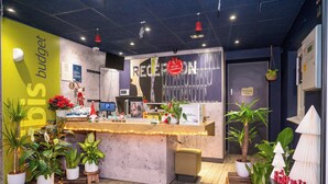 A reception desk with a sign reading "RECEPTION" and "Restricted Area" on the door. There are potted plants around the desk and a Christmas decoration. - ibis budget London Barking (Barking)