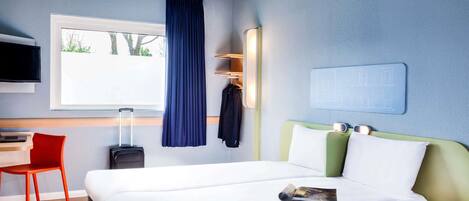 A modern hotel room with a large bed, a desk, a chair, a TV, and a window with a curtain.