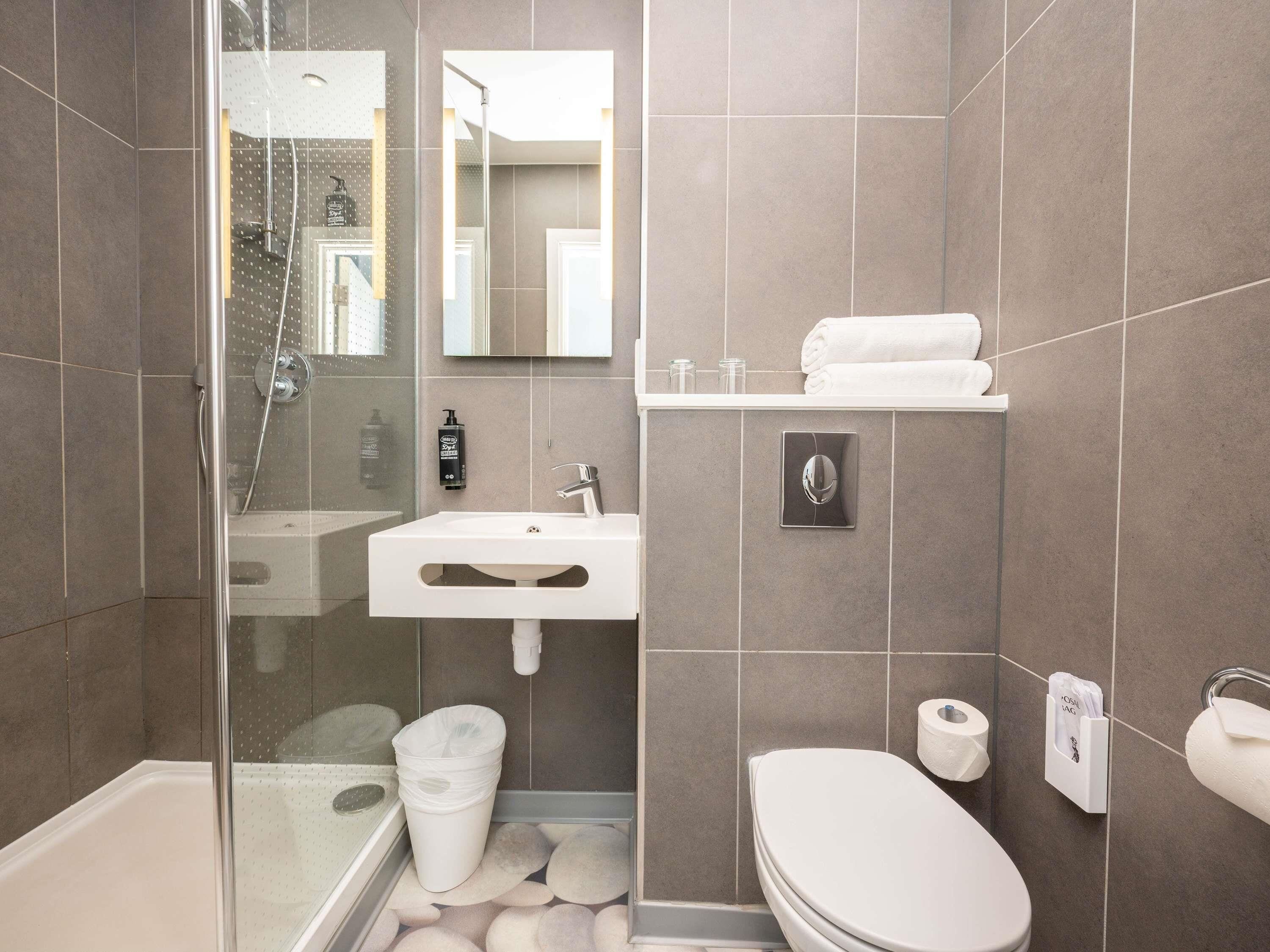 A modern bathroom with a glass shower enclosure, a white sink, a toilet, and a towel rack.