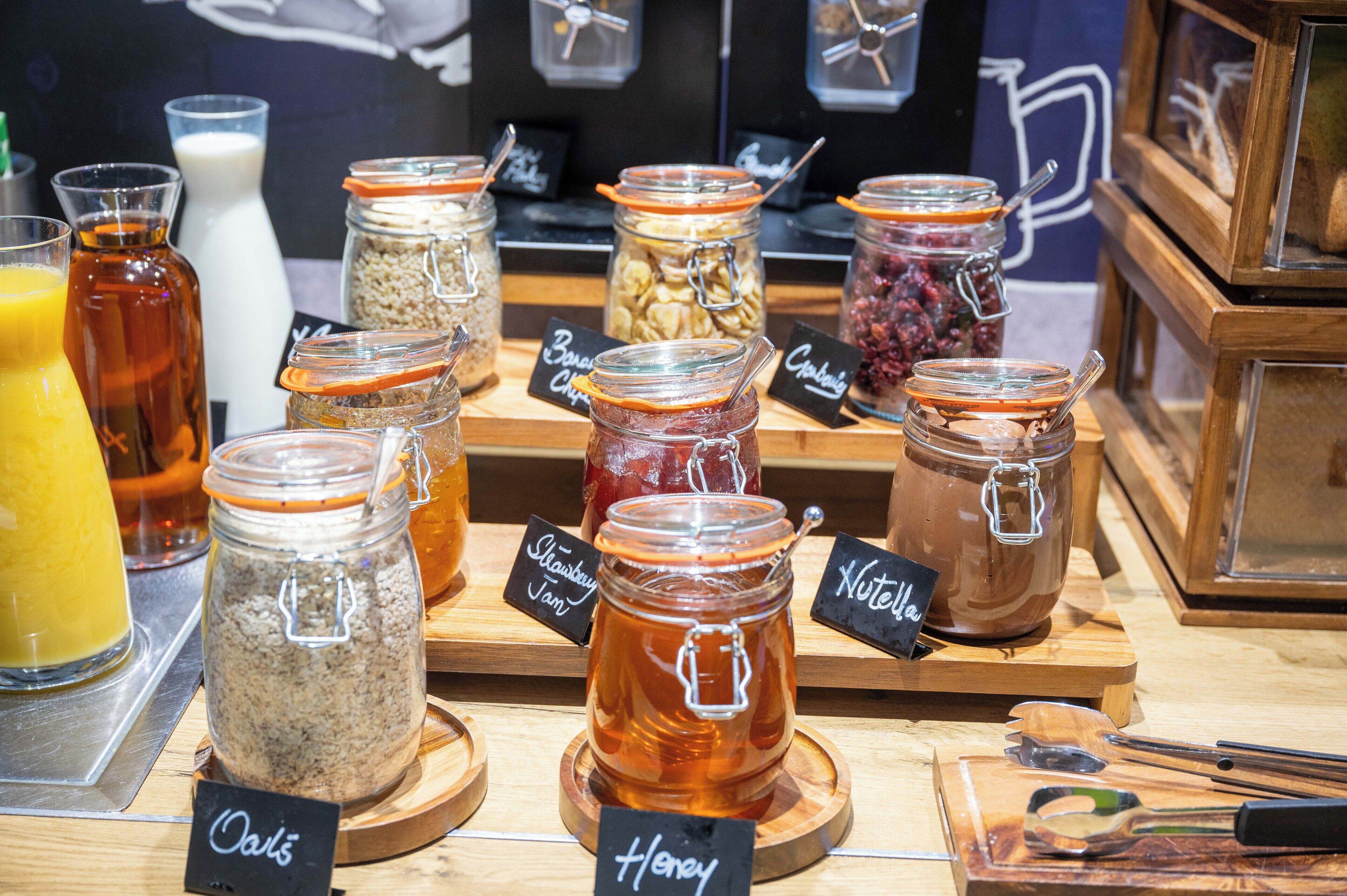 A display of various food items in jars with labels, including oats, honey, and jam.
