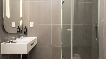 A modern bathroom with a glass-enclosed shower, a white sink, and a large mirror.