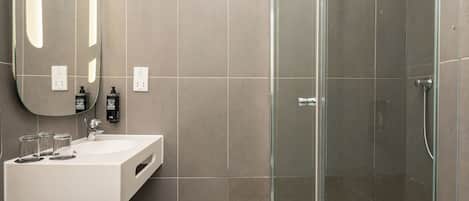 A modern bathroom with a glass-enclosed shower, a white sink, and a large mirror.