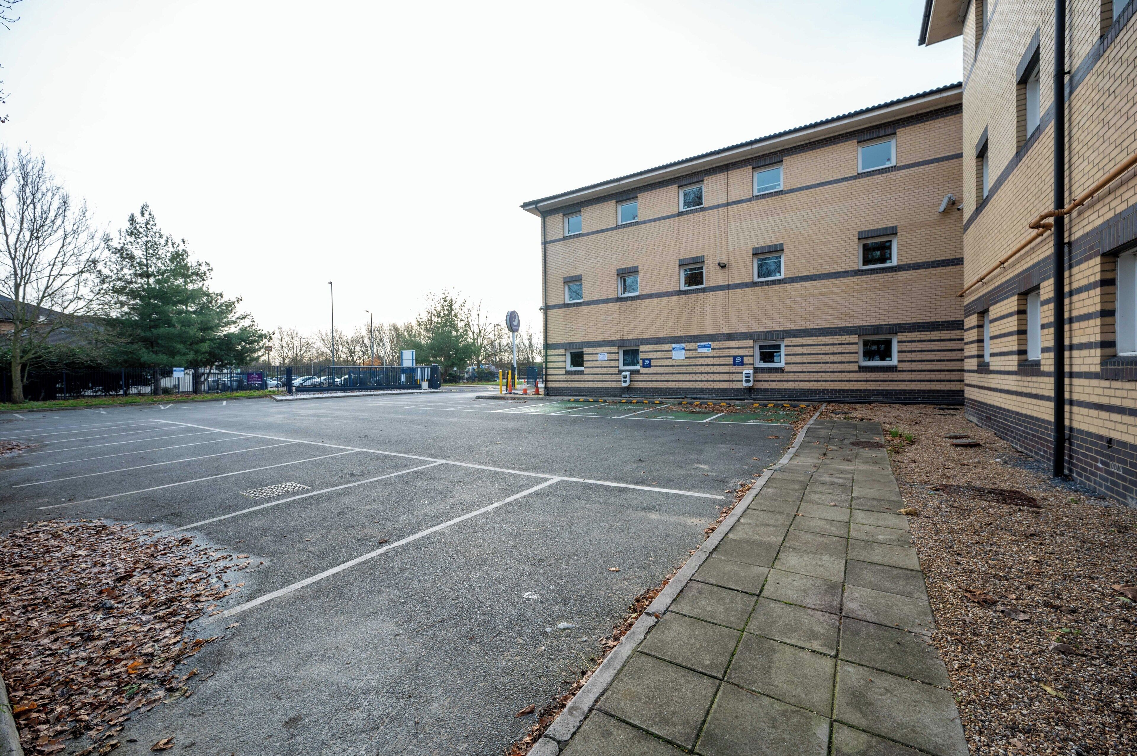A parking lot with marked spaces and a building with multiple windows and a brick facade.