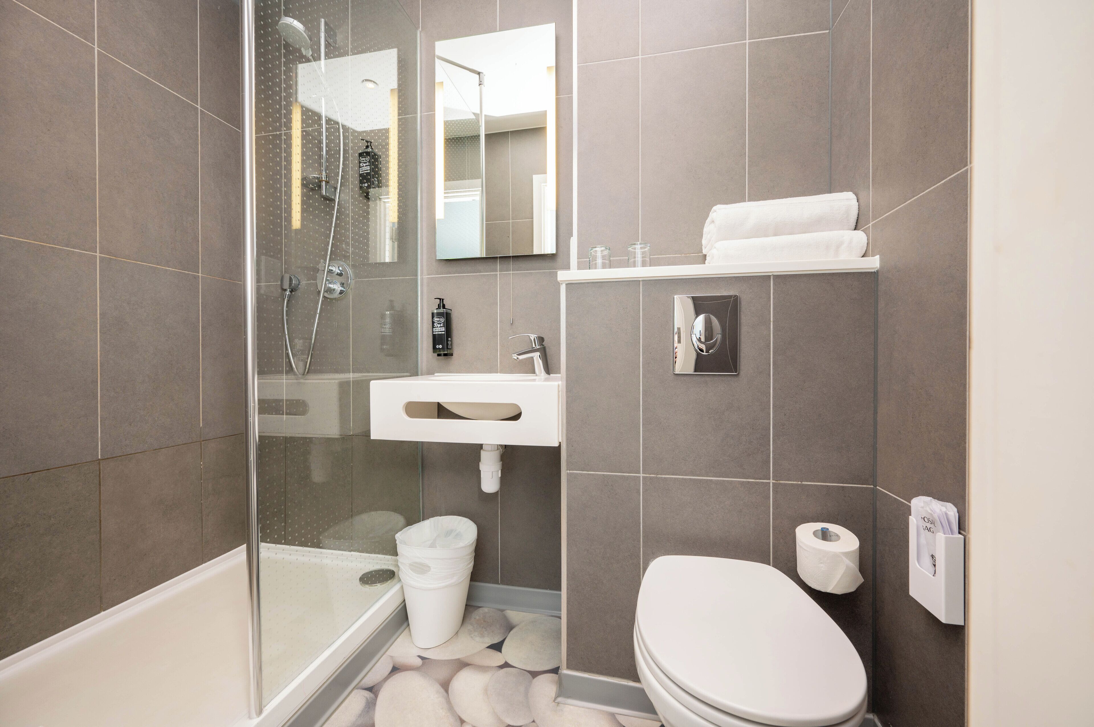 Ein modernes Badezimmer mit einer Duschkabine, einem weißen Waschbecken und einer Toilette.